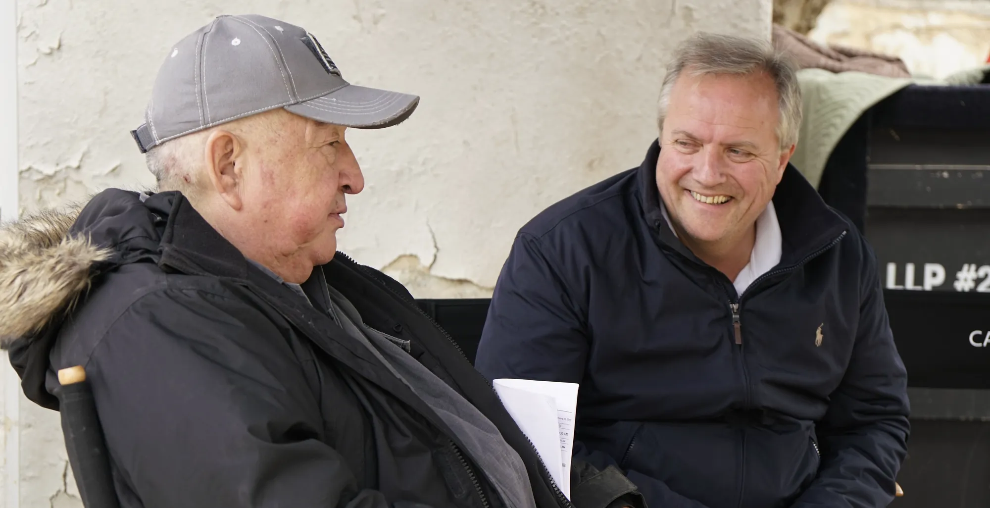 Tom Reeve on set with Graham Greene, script pages in hand, in conversation between takes